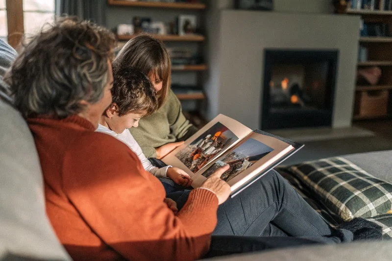 A family gathered on a couch, looking through a photo album together