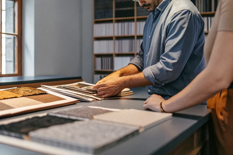 A sourcing manager comparing different photo album samples at a desk