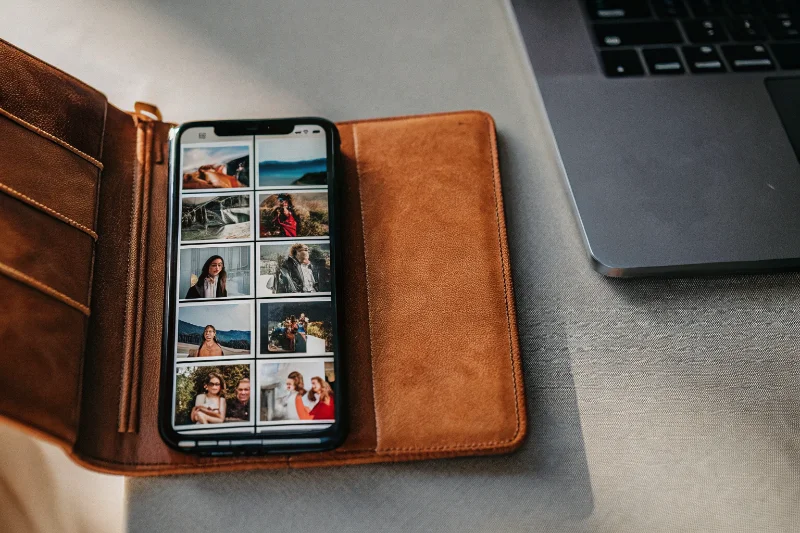A classic photo album next to a smartphone displaying photos