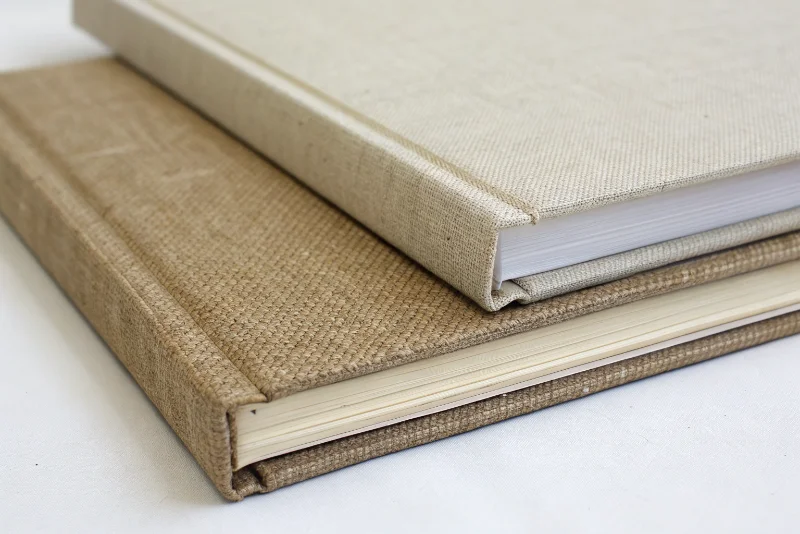 A close-up shot showing the texture of a linen cover next to a thick, acid-free cardstock page