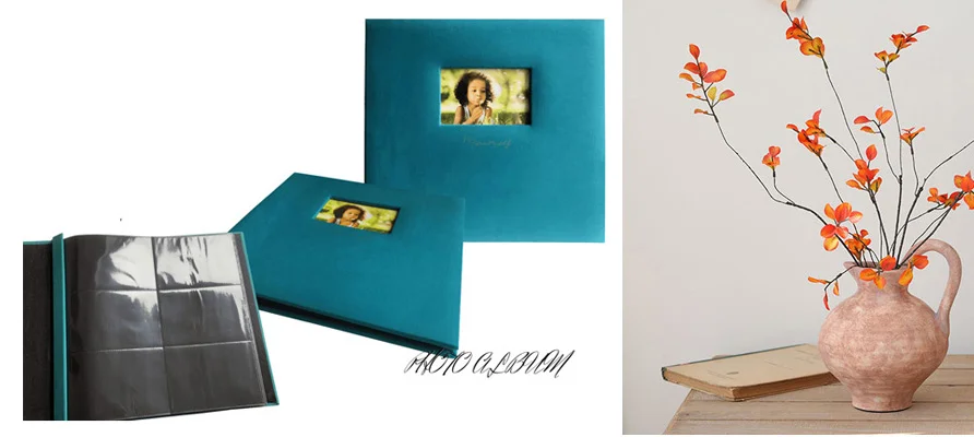 Teal photo album showcasing internal plastic sleeves for photo protection beside a ceramic vase with orange daisy flowers.