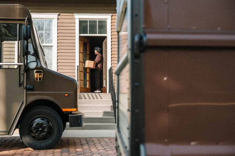 A delivery truck from a courier like UPS or FedEx in front of a house
