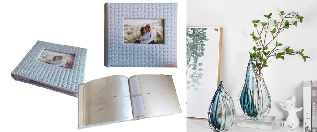 A textured photo album with a framed cover photo, open pages, and decorative glass vases with greenery in a modern setting.