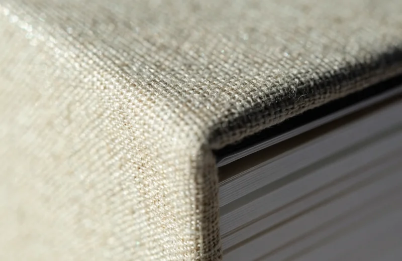 A close-up shot showing the texture of a high-quality linen cover and thick album paper